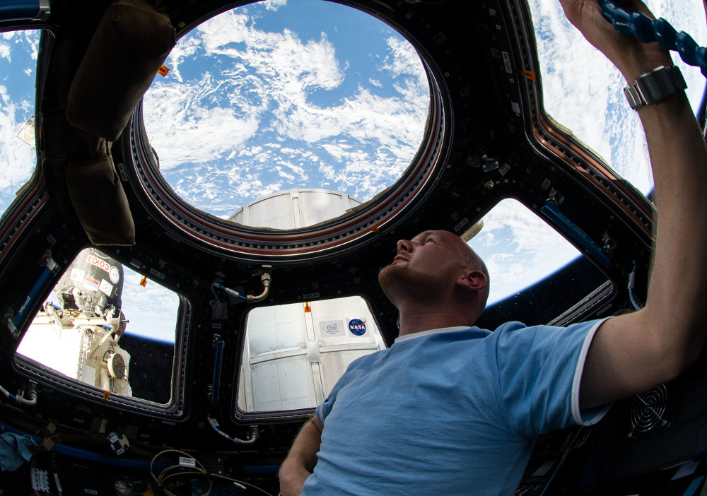 астронавт смотрит на Землю из иллюминатора